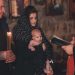 A touching moment during an Orthodox baptism ceremony with a priest, parents, and baby.