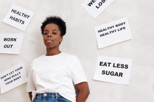 African American woman stands near motivational health slogans on the wall, promoting a positive lifestyle.